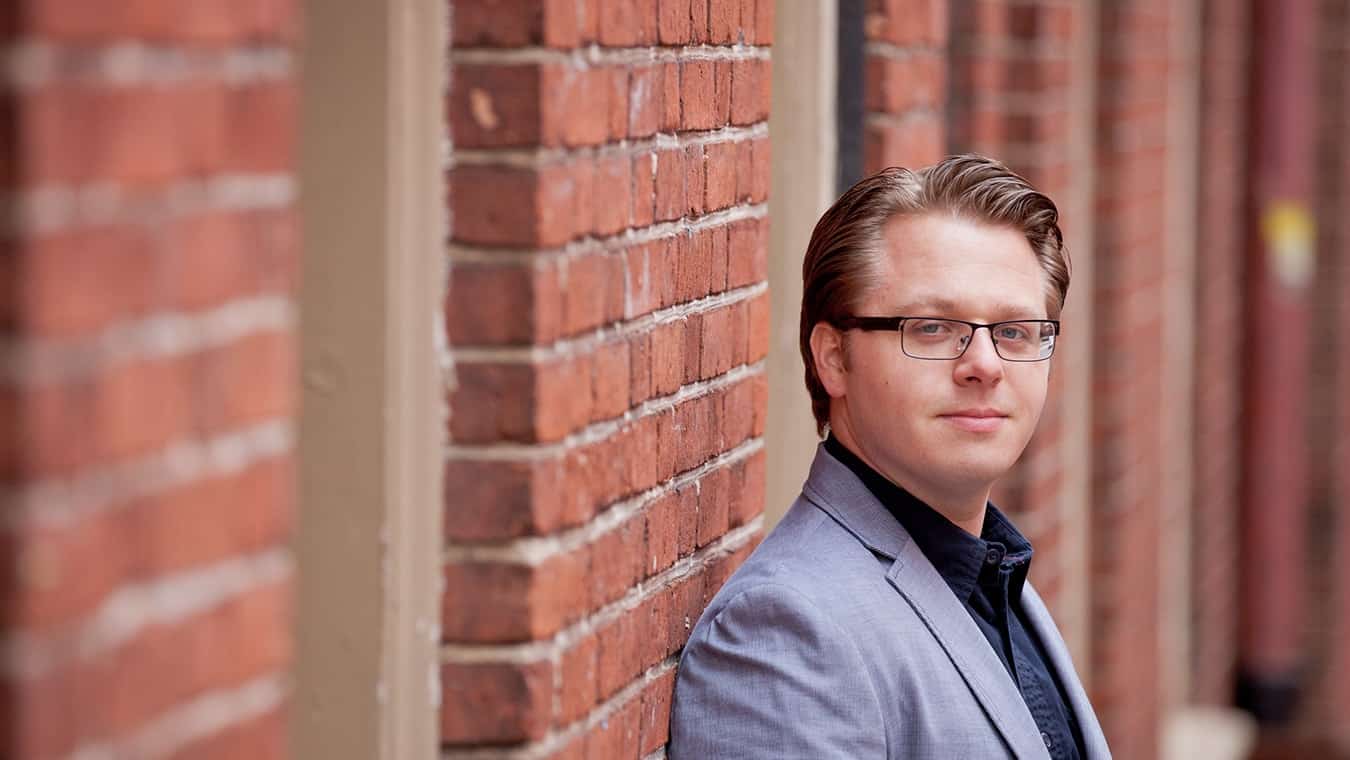 An alumnus of Regent's online PhD in Counseling and Psychological Studies – Biblical Counseling program posing against a brick wall on the Virginia Beach campus