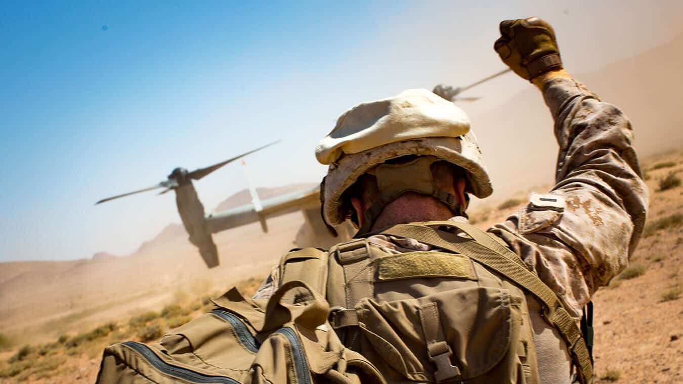 A soldier directs a helicopter in a desert who studied online in Regent's MA in National Security Studies - Middle East Politics program