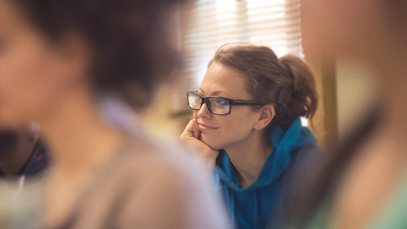 A student smiling and listening in class for the Master of Divinity in Theology & Ministry (M.Div.) in Interdisciplinary Studies degree program offered by Regent University.