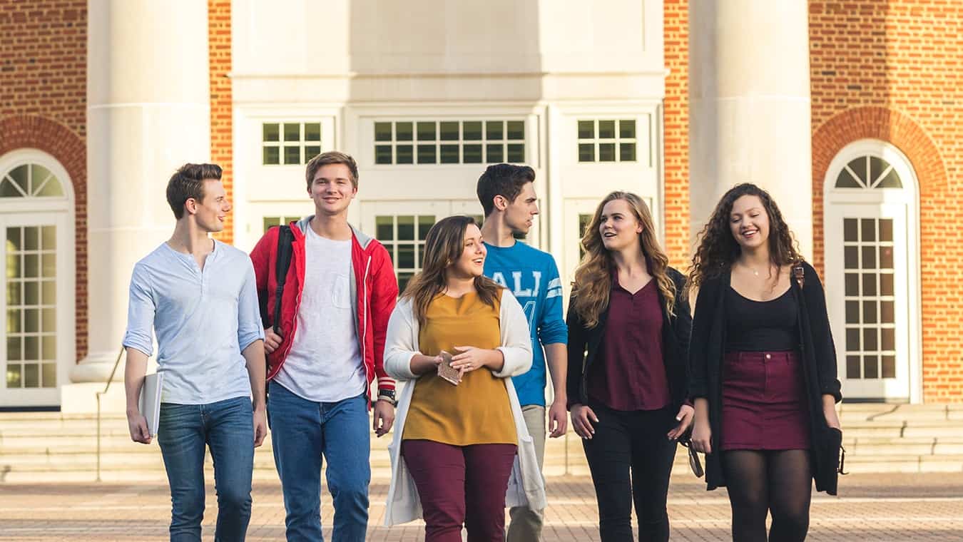 Six students walking outside of the Communications building at Regent University.