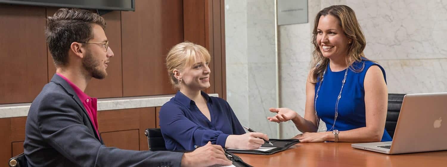 Three students in Regent University's MAOL for human resources degree meeting in an office space.