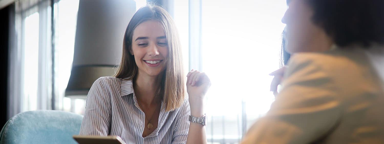 A girl smiles while looking at a device: Pursue your MA in Christian Discipleship program at Regent University.