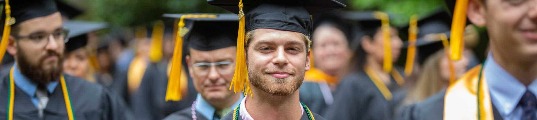 A closeup of a Regent University graduate in regalia, lined up and ready for the commencement ceremony.