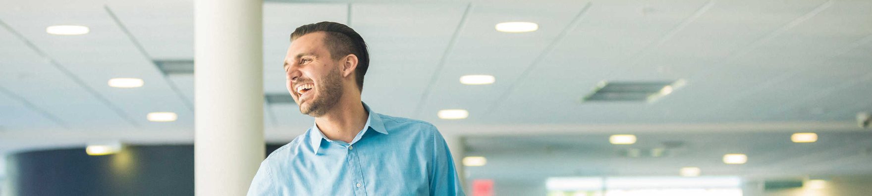 A Regent University student inside a campus building looking out a window and smiling.