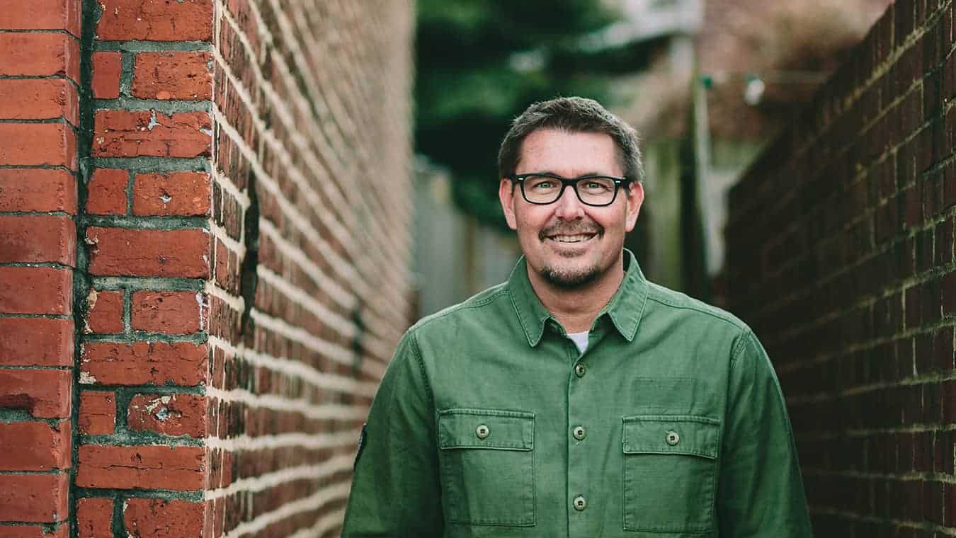 Alumnus Mark Batterson at Regent wearing a green shirt with a brick wall background