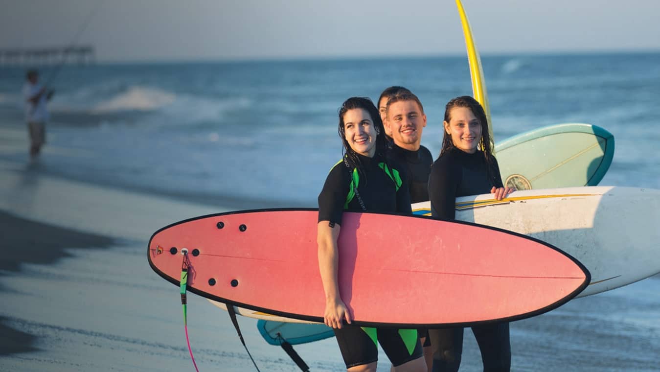 Regent's college students with surfboards at the beach.