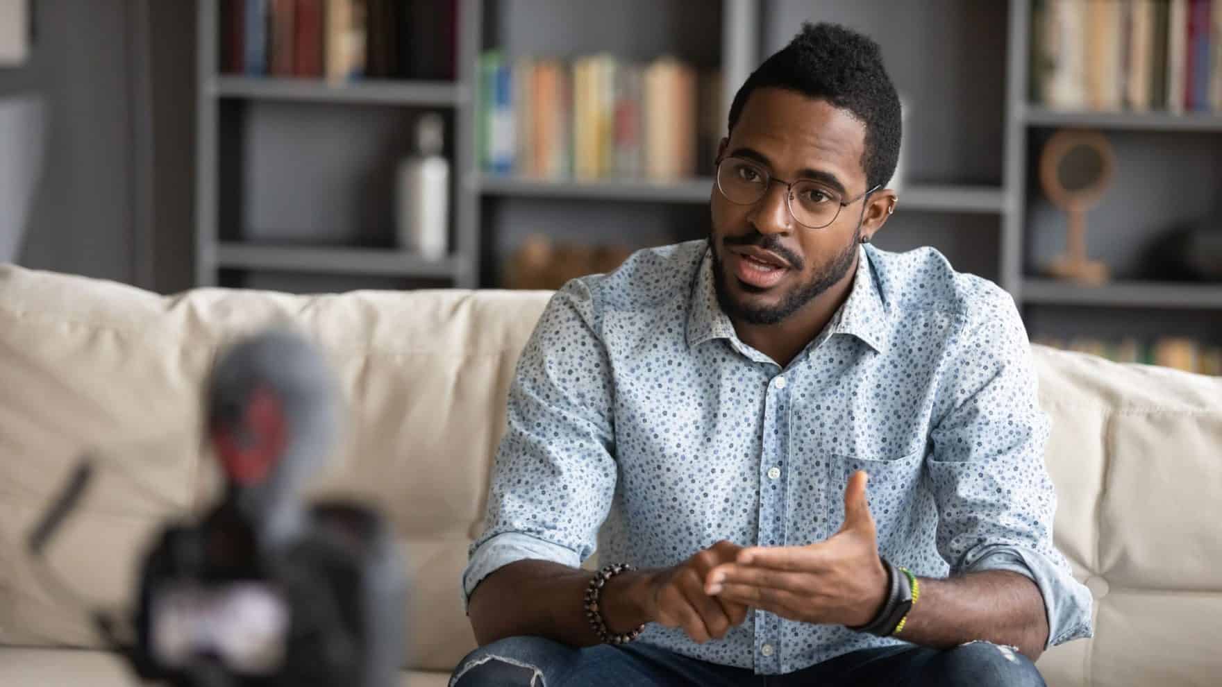 A Regent University student in the Online Ministry program filming himself speaking from a couch with video camera equipment.