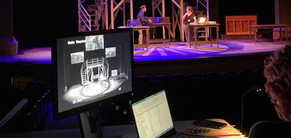 A director watches a practice performance from off stage.