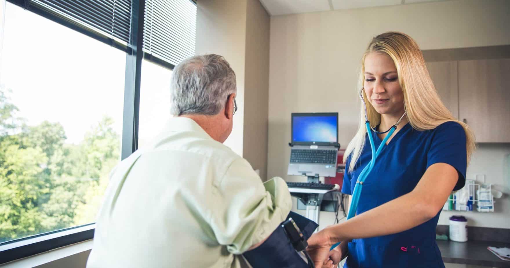 A Regent University nursing student taking the blood pressure of a patient, which is a part of the School of Nursing that was ranked #3 in Hampton Roads.