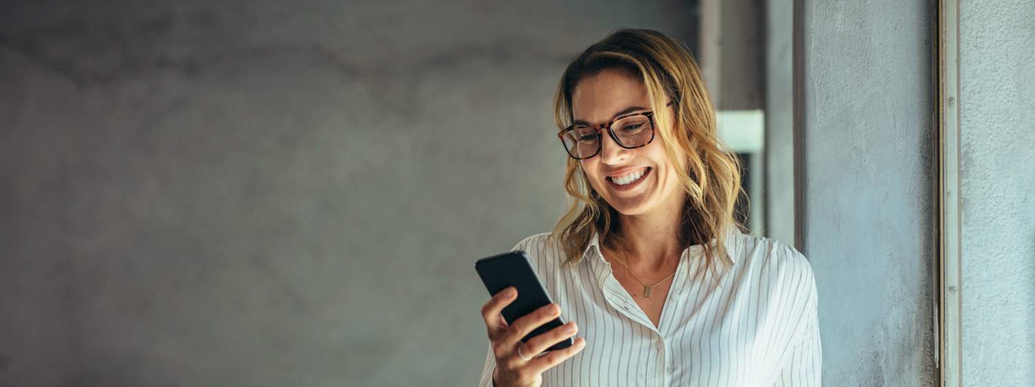 A photo of a student holding a cellphone: Learn more about pursuing a communications degree online or in person at Regent University.