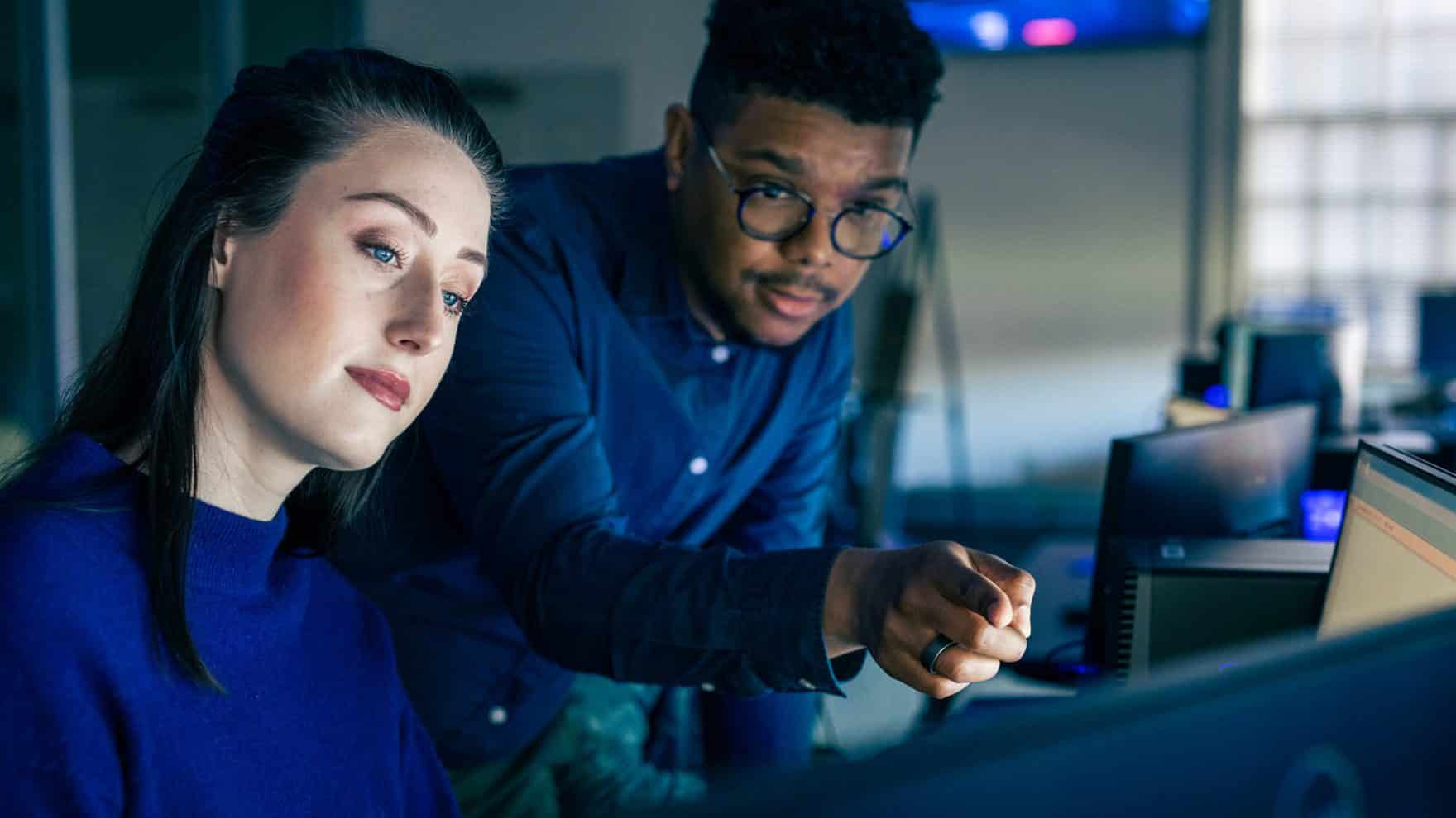 Two students at Regent University in the Undergraduate Certificate in Cyber Practitioner Preparation program working together on computers.