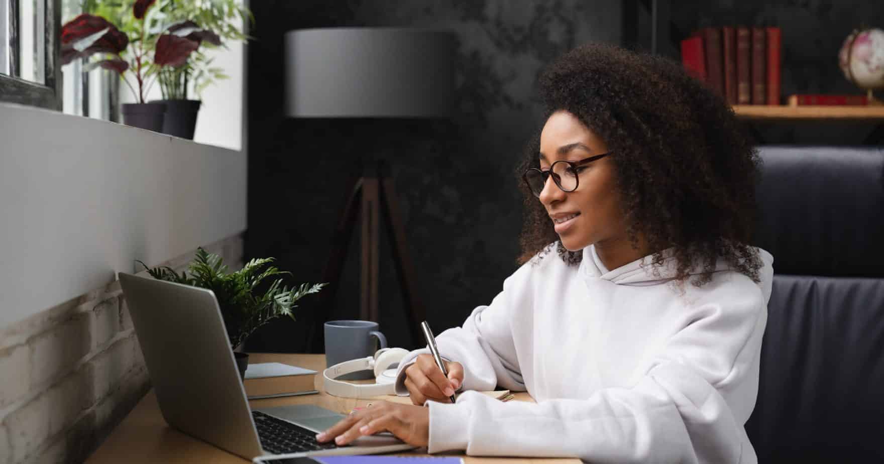 A student working on a laptop: Regent will transition to the Canvas LMS in Fall 2023.