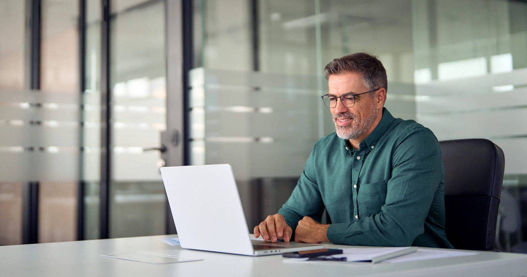 A man working on a laptop in an office.