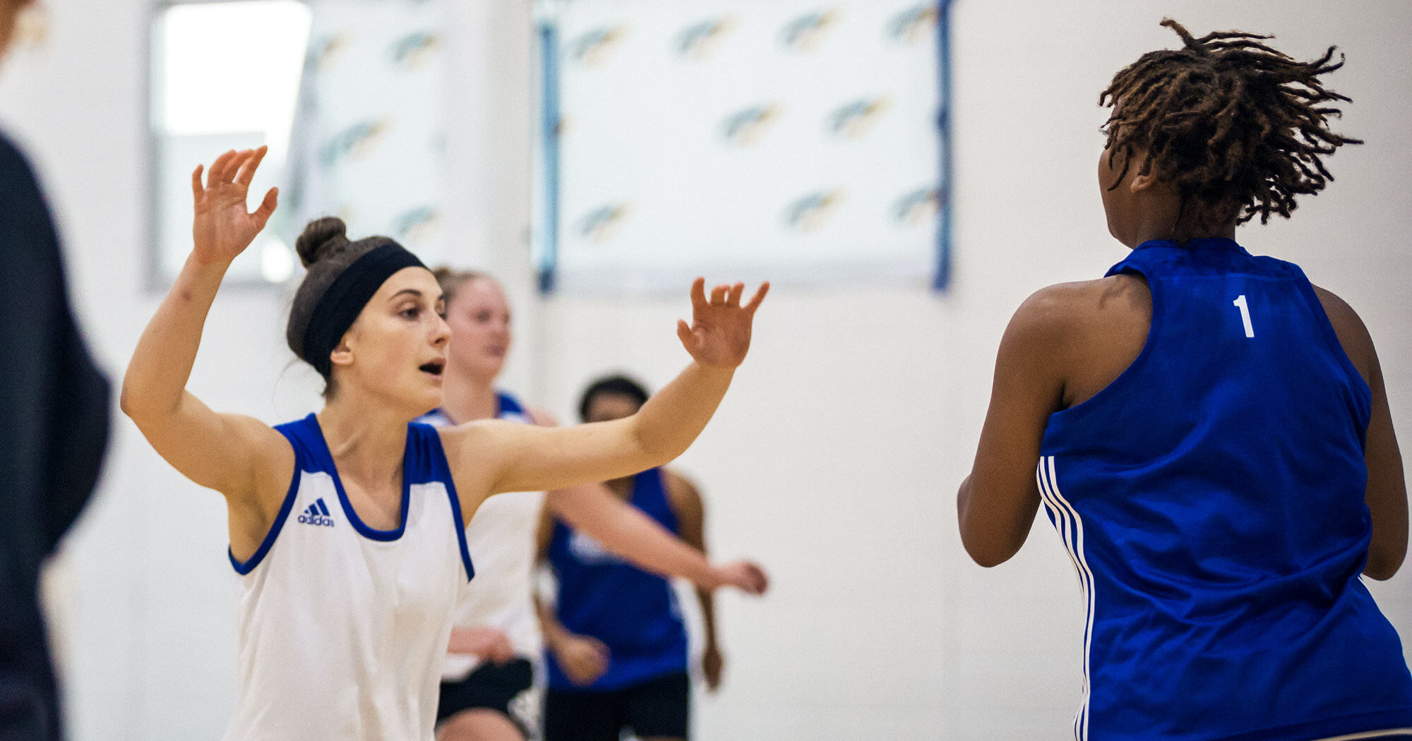 Regent Royals' women's basketball team member playing defense with arms up and focused with instruction from new head coach Donte Minter.