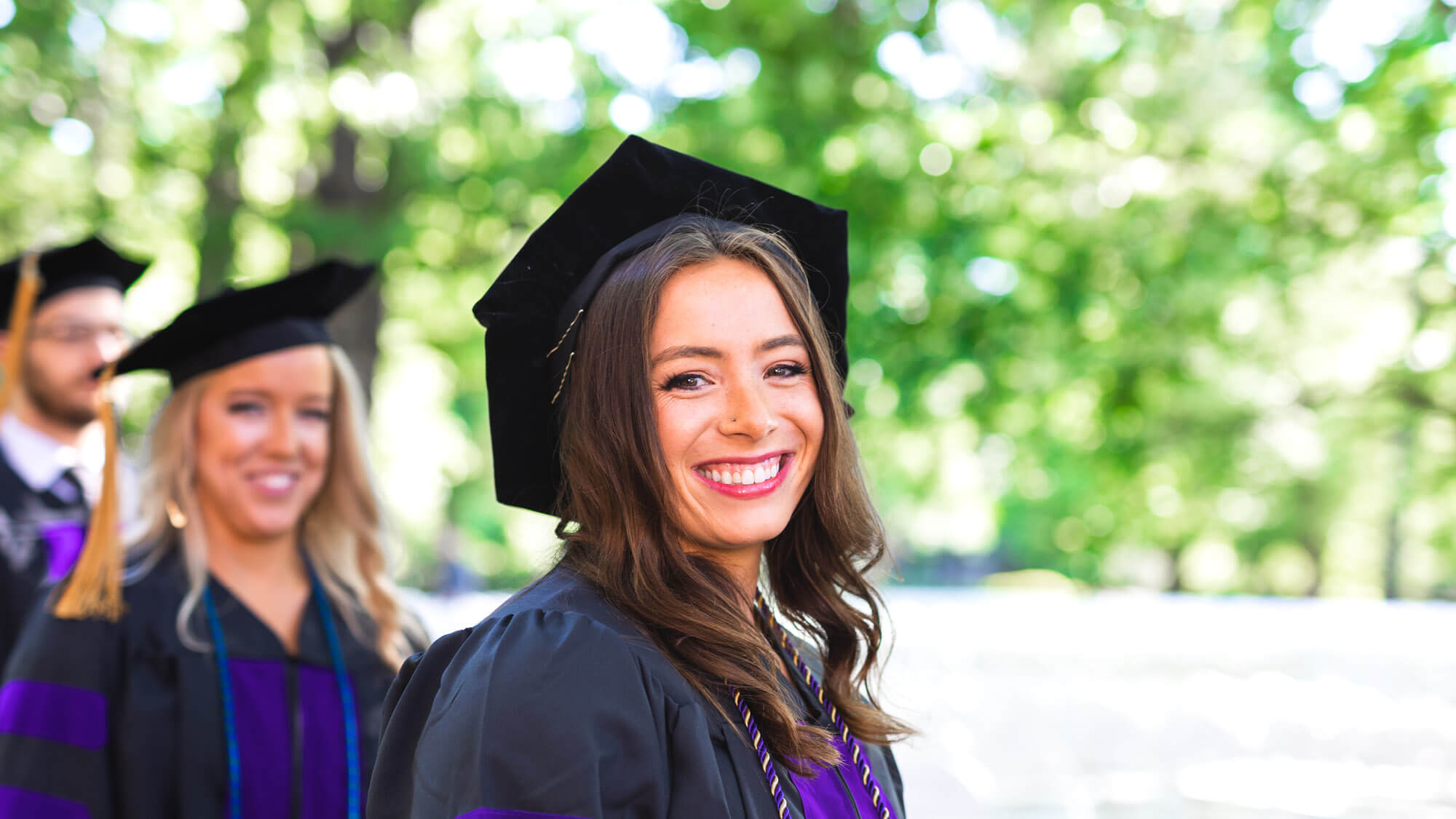 A graduate smiling at the commencement of Regent University law schools in Virginia.